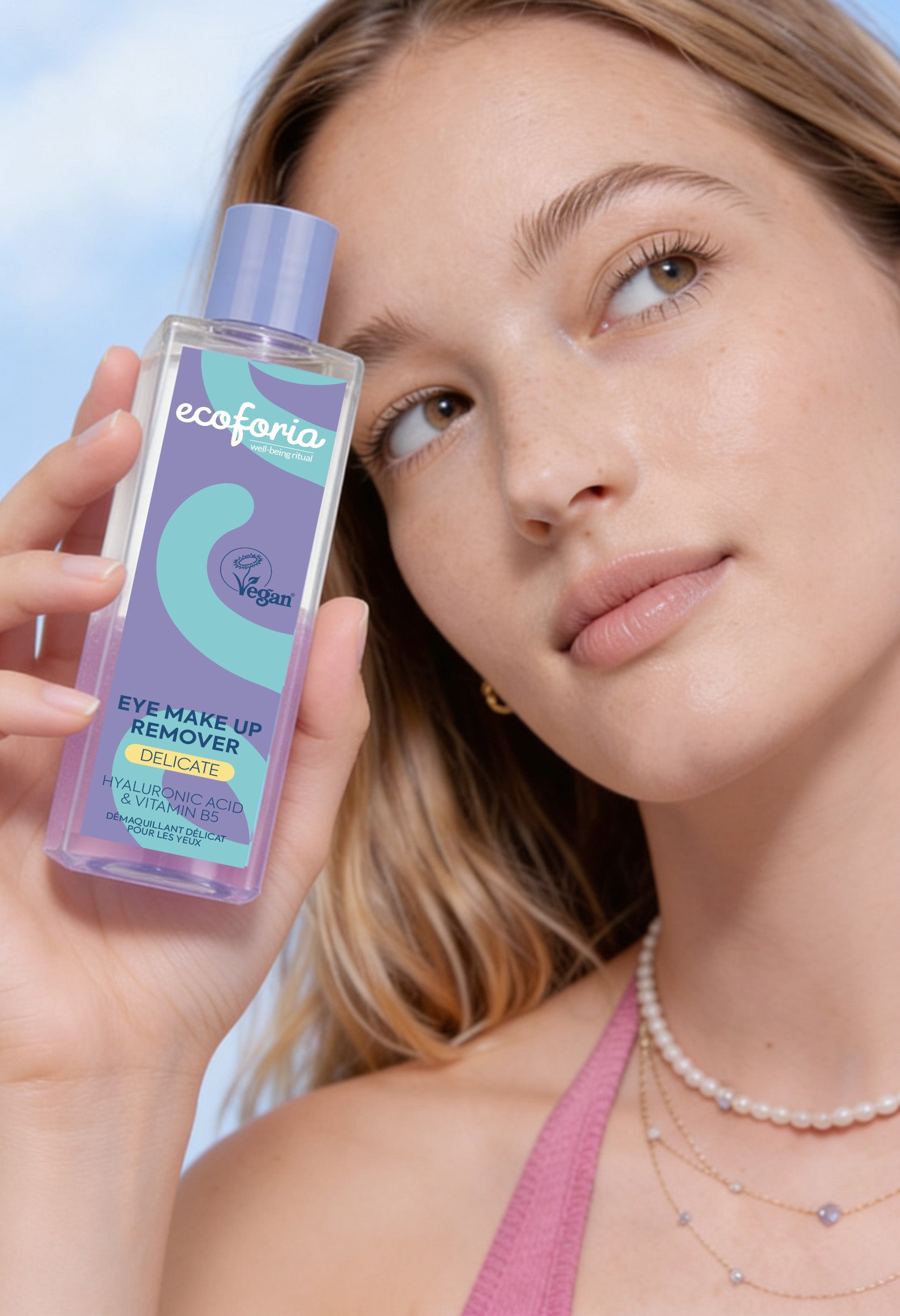 Woman holding ecoforia eye makeup remover bottle with a close-up of her face.